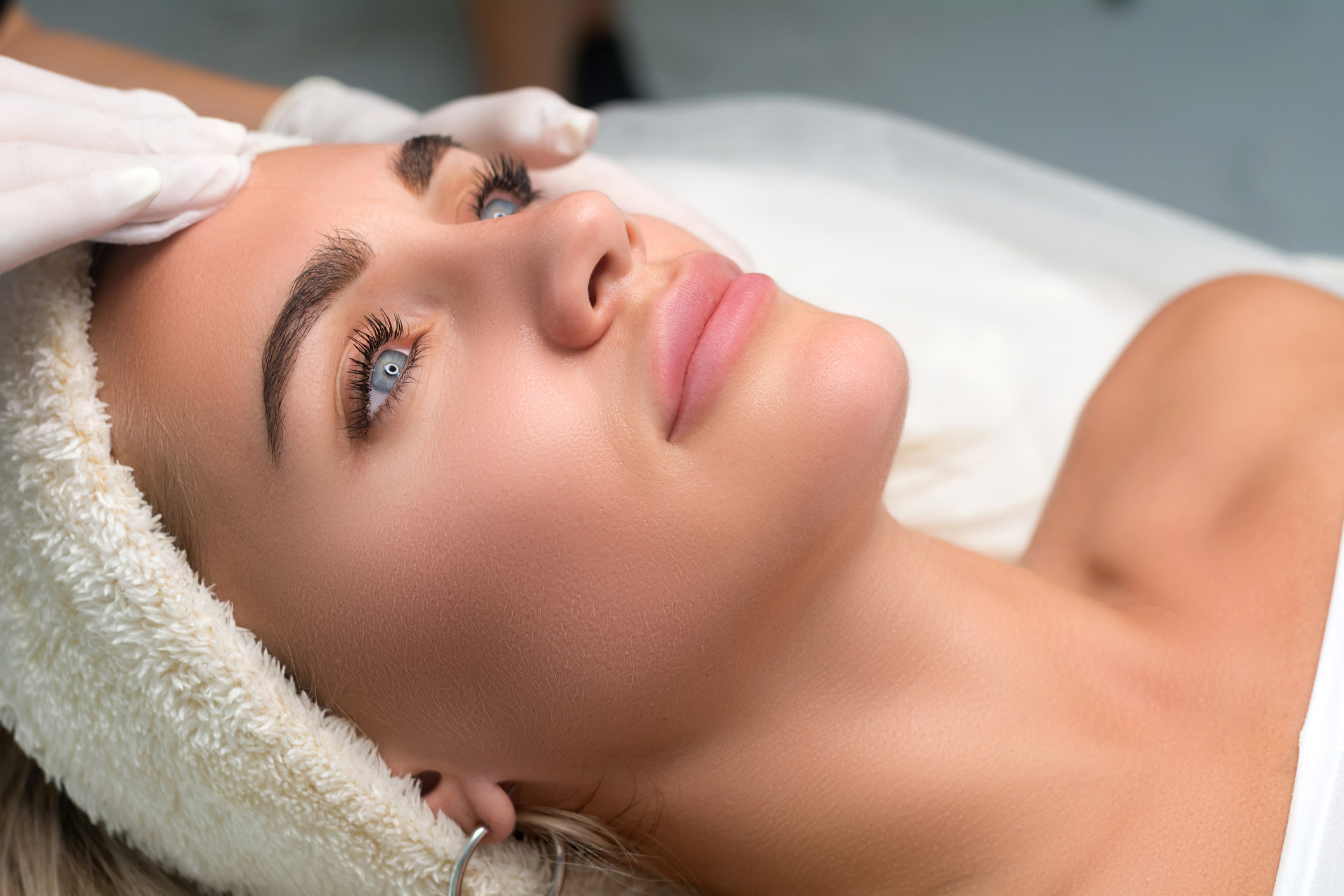 Young woman in a beauty salon. The beautician makes a facial cleansing procedure